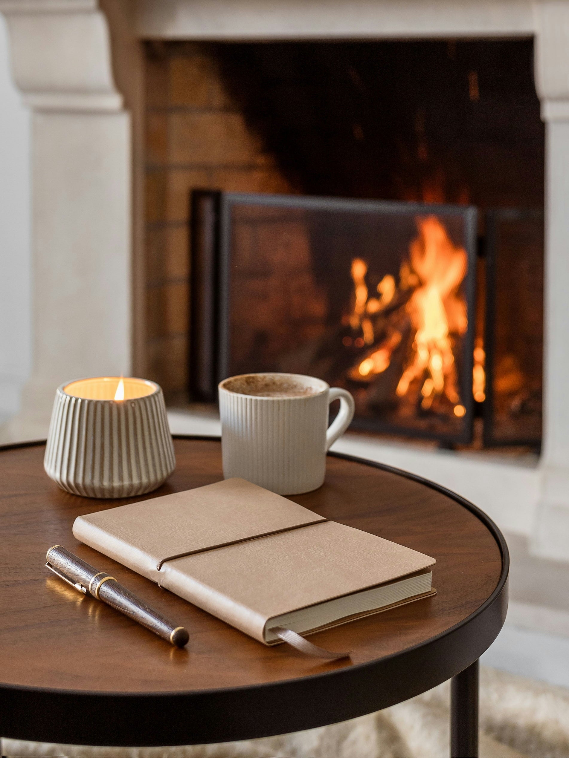 a notebook, mug, and candle in a table