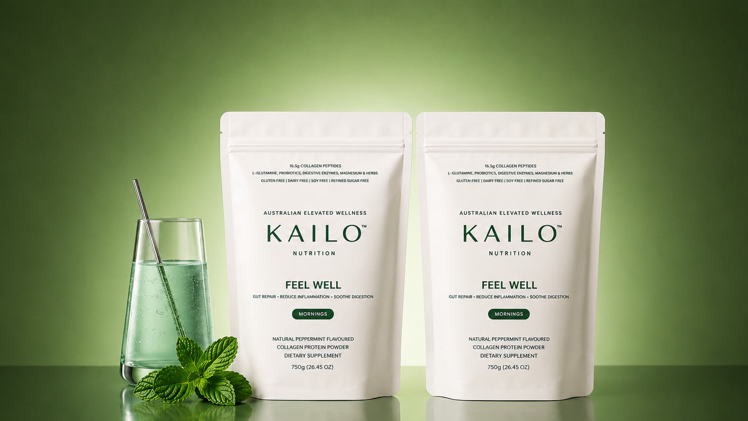 Two white stand-up pouches of KAILO Feel Well Australian Super Melted Complex Powder are displayed on a reflective green surface against a green gradient background, with a glass of green drink and mint leaves as props.