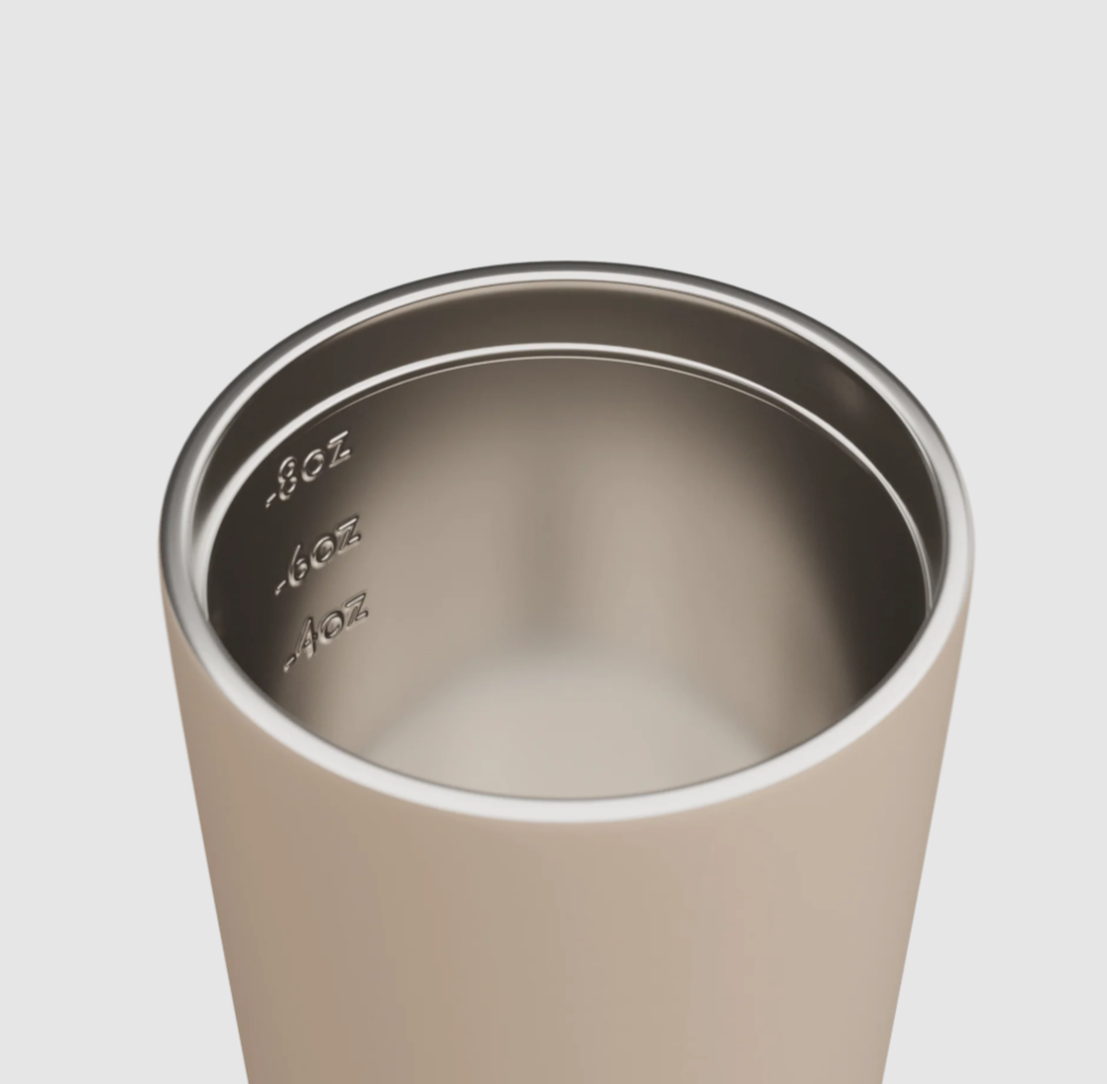 Close-up of a stainless steel tumbler with measurement markings on a plain background.