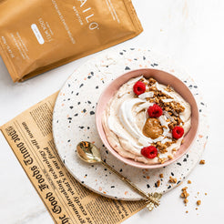 Bowl of yogurt with toppings on a plate with a newspaper underneath, next to a package labeled KAILO