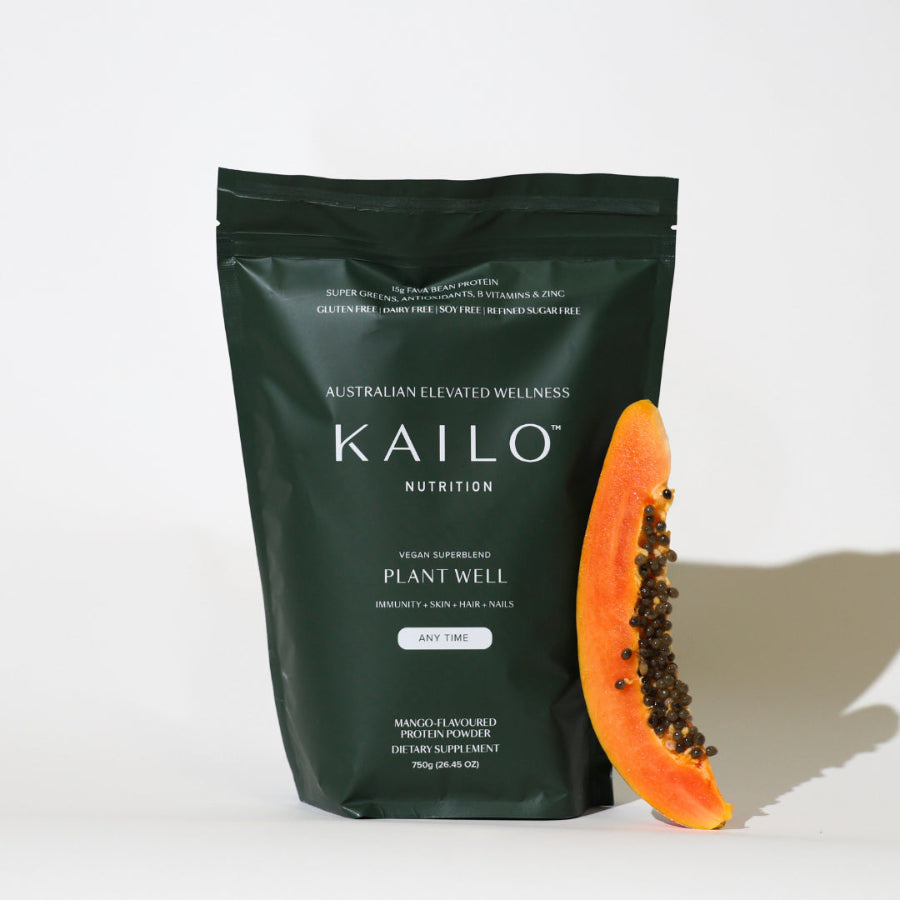 A package of KAILO Nutrition Plant Well, a plant-based protein super greens powder, in a mango flavor, 750g size, with a piece of fruit displayed next to it.