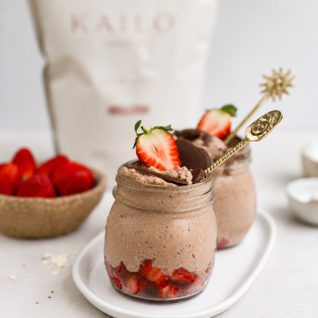 Chocolate mousse in jars with strawberries on a white plate, KAILO bag in the background.